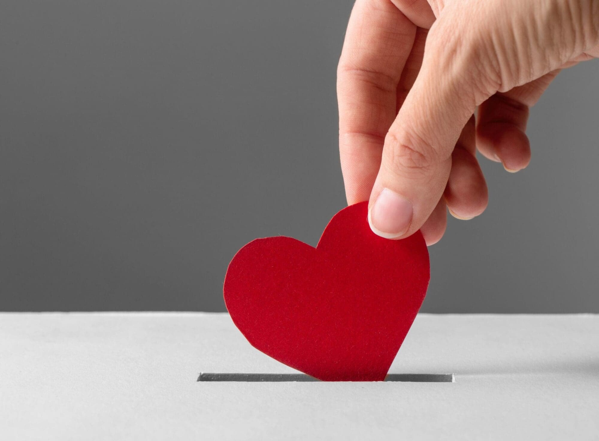 Hand putting red paper heart into box
