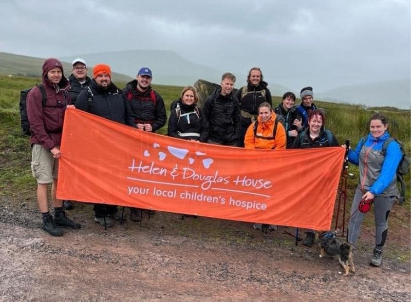 A group of trekkers holding up a large Helen & Douglas House charity banner.