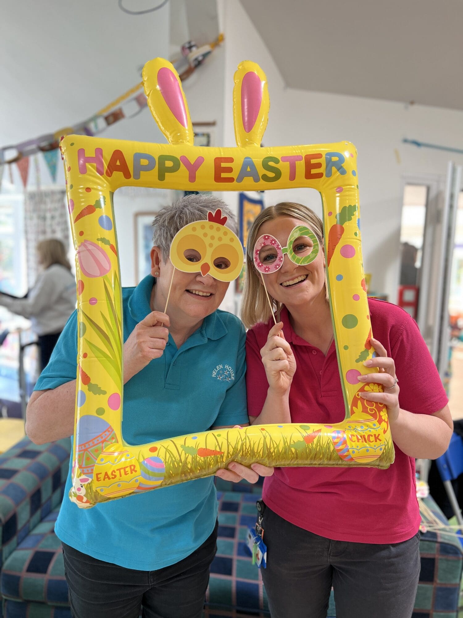 2 ladies smiling at the camera holding an easter frame