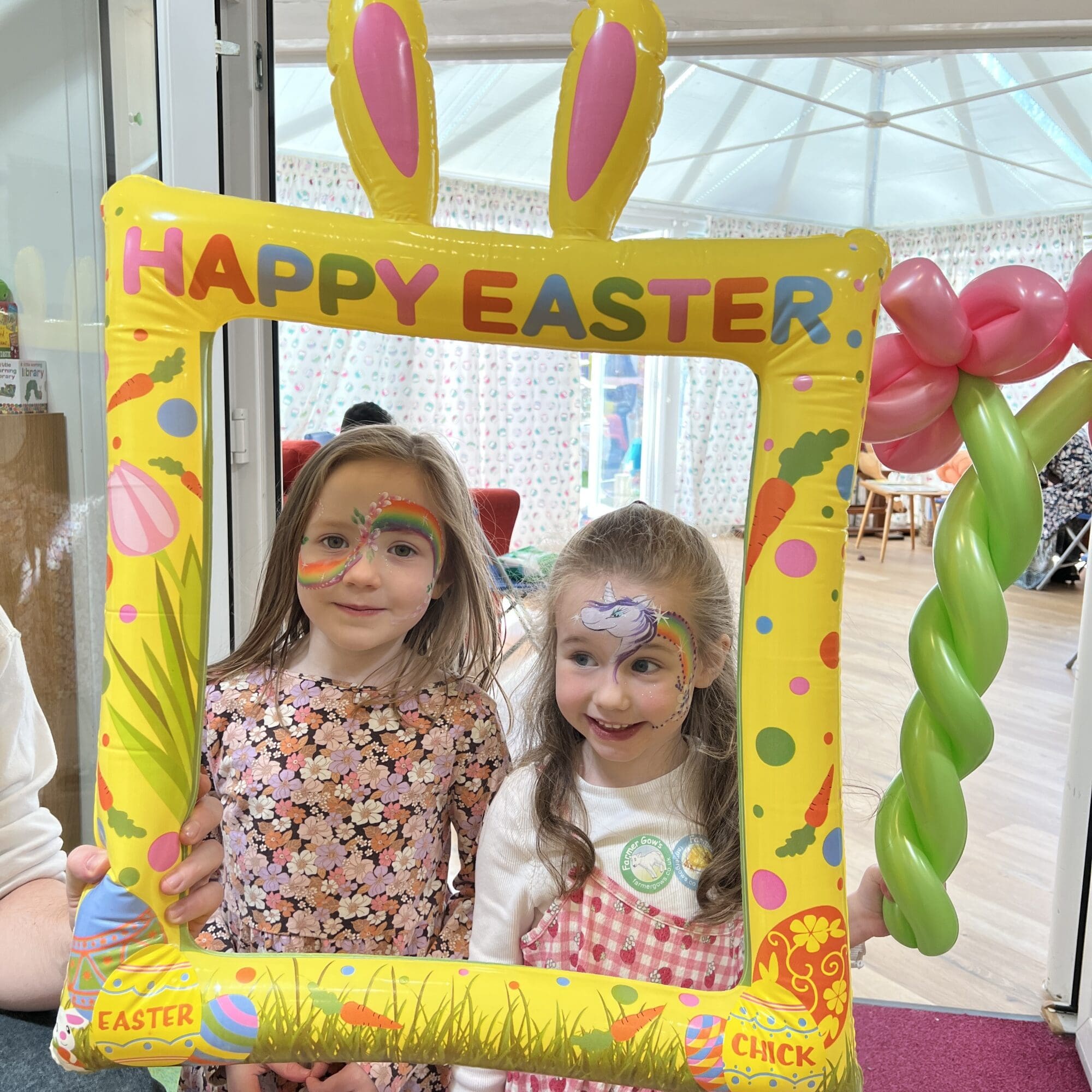 2 girls standing holding an easter frame with facepaint on